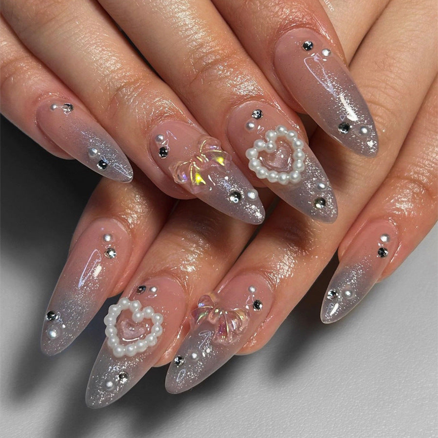 Almond nail polish with crystal bow and pearl heart decoration